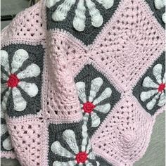 a crocheted blanket with flowers on it sitting on top of a couch next to a pillow