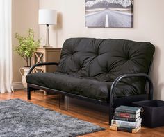 a living room with a futon couch and books on the floor next to it