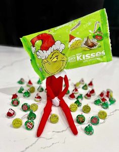 an elf is holding up a bag of kissese candies on top of a table