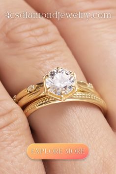 a woman's hand holding a gold ring with a white diamond in the center