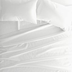 a bed with white sheets and pillows on it