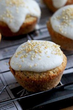 some cupcakes with white frosting and sprinkles are on a cooling rack