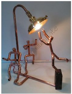 a lamp that is sitting on top of a metal stand with pipes coming out of it