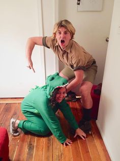 two people in costumes standing on the floor with their mouths open and one person sitting on the ground