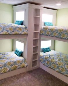 two bunk beds with blue and green pillows in a room that has carpeted flooring