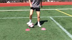 a young man standing on top of a soccer field holding a red and white ball