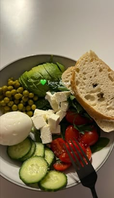 a plate with bread, cucumbers, tomatoes and other food items on it