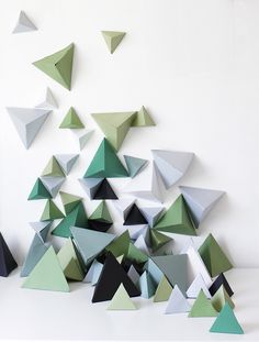 an arrangement of green and grey triangles on a white wall