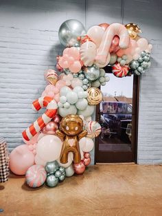 a balloon arch in the shape of a house with balloons all over it and a teddy bear