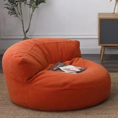 an orange bean bag chair sitting on top of a rug next to a potted plant