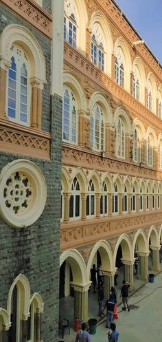 people are walking around in front of an old building with arches and arched doorways