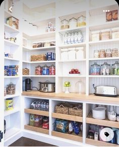 an organized pantry with white shelving and wooden shelves