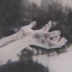 two hands reaching out to touch each other with white powder on their palms and fingers