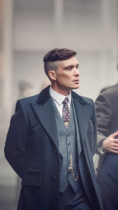 a man in a suit and tie walking down the street with his hand on his hip