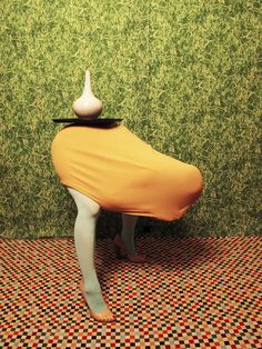 a white vase sitting on top of a wooden bench in front of a green wall