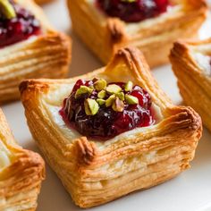 small pastries with cranberry sauce and pistachio toppings on a white plate