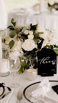 the table is set with white flowers and place settings