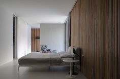 a bed sitting in the middle of a bedroom next to a wooden wall