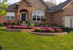 a house with landscaping in front of it and lots of flowers around the driveway area