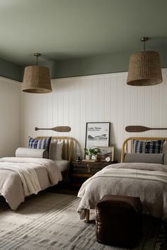 two twin beds in a bedroom with white walls and wood trimmings on the ceiling