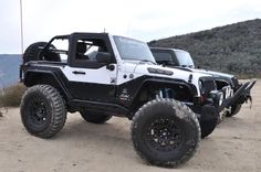 a white and black jeep parked on top of a dirt field