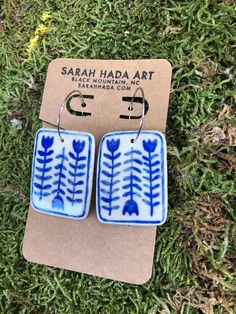 two blue and white earrings sitting on top of a grass covered field next to a cardboard box