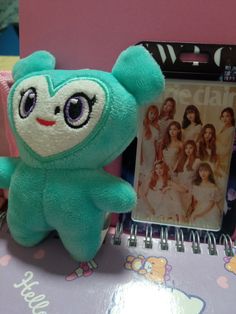 a blue teddy bear sitting on top of a desk next to a notepad and album