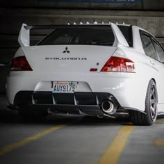 the back end of a white car parked in a parking garage