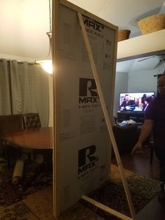 a man standing in front of a large cardboard box on the floor next to a table