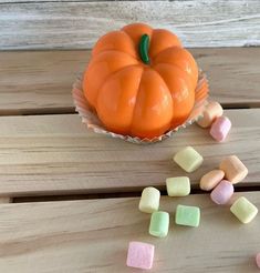 an orange pumpkin sitting on top of a wooden table next to marshmallows