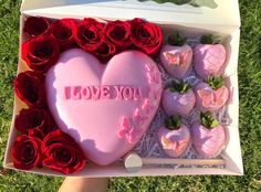 someone holding a heart shaped box with strawberries and chocolates in the shape of hearts