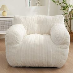 a white bean bag chair sitting on top of a hard wood floor next to a window