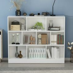 a white book shelf with books and vases on it