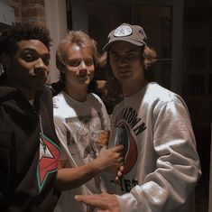 three young men standing next to each other posing for the camera with pizza in their hands