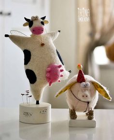 two stuffed animals are sitting on top of a white table and one is wearing a hat