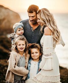 a man standing next to two women and two children on top of a rocky beach