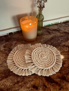 two wicker coasters next to a candle on a table