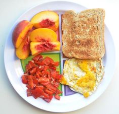 a white plate topped with toast, eggs and fruit next to slices of peaches