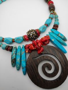 Beautiful ethnic style choker necklace, handmade with various materials: howlite, coral, jasper, hematite, wood. The central element of the necklace is a large pendant made of dark walnut-coloured cut-out wood. The turquoise blue of the jasper and the red of the coral contrast with each other and create a beautiful color combination. The necklace is double stranded, made up of different pearls and shells that create intersections of beautiful shapes and colors. The necklace is rigid but at the same time adheres perfectly to the neck and has an adjustable closure with a 7 cm extension. The necklace is very showy and colourful, in the colors of blue, red and brown, it is reminiscent of summer, the sea...suitable for a low-cut dress for a special occasion. It is a unique design created by me Handmade Artisan Turquoise Necklace For Festivals, Turquoise Wooden Beads Necklace For Festivals, Traditional Turquoise Beaded Necklaces With Wooden Beads, Traditional Turquoise Beaded Necklace With Wooden Beads, Spiritual Turquoise Necklaces With Wooden Beads, Spiritual Turquoise Necklace With Wooden Beads, Adjustable Bohemian Red Coral Necklace, Handmade Turquoise Necklace With Red Coral, Bohemian Turquoise Necklace With Red Coral For Gift