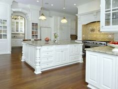 a large kitchen with white cabinets and wood floors