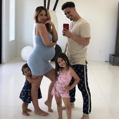 a man taking a photo with his pregnant wife and two children in front of him