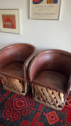 two brown leather chairs sitting on top of a rug