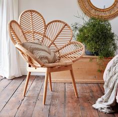 a wicker chair sitting on top of a wooden floor next to a potted plant