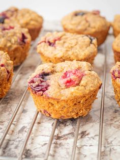 muffins cooling on a rack with blueberries and cranberry toppings