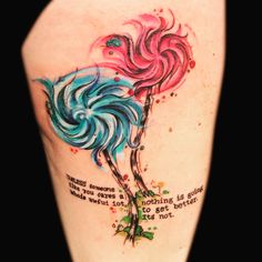 a colorful bird tattoo on the back of a woman's left arm with words written below it