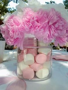 pink carnations and marshmallows in a jar on a table