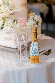 a bottle of champagne sitting on top of a table next to two wine glasses and a cake