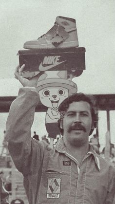 a man holding up two pairs of shoes on top of his head in front of a crowd