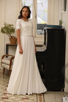 a woman in a white dress standing next to a piano