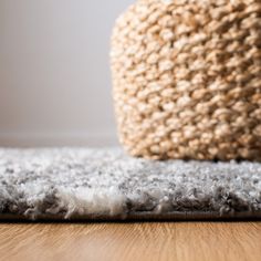 an area rug is on the floor next to a woven basket and a wooden floor